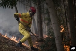 A firefighter works on an active fire on a hillside outside the village of Monchique, in southern Portugal's Algarve region, Monday, Aug. 6, 2018.