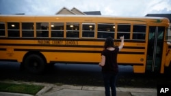 Rachel Adamus waves goodbye to her two children, Paul and Neva, as they ride the bus on the first day of school on Monday, August 3, 2020, in Dallas, Georgia, USA. (AP Photo/Brynn Anderson)