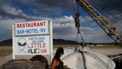 In this July 22, 2019 photo, Grace Capati looks at a UFO display outside of the Little A'Le'Inn, in Rachel, Nevada, the closest town to Area 51.