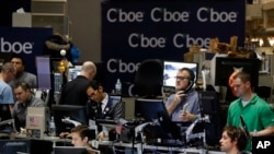 Traders work in a trading pit at the Chicago Board Options Exchange, Monday, Dec. 11, 2017, in Chicago, as they trade futures and options unrelated to bitcoin. Trading in bitcoin futures began Sunday on the CBOE. (AP Photo/Kiichiro Sato)