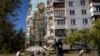 ARCHIVO - Una mujer alimenta palomas frente a un mural del artista callejero ucraniano Eugene Gladenko que muestra al soldado ucraniano caído Maksym Bordus, en medio del ataque de Rusia a Ucrania, en Kiev, Ucrania, el 8 de octubre de 2024.