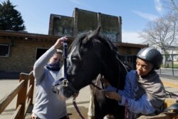 Tasneem Aly, right, and General manager Naomi Howgate take the harness off Bailey after a riding lesson at Ebony Horse Club in Brixton, south London, April 18, 2021