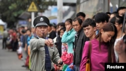 FILE - A security guard blows a whistle at a bus stop outside a railway station Hefei, Anhui province during a busy time, Oct. 7, 2013. (Reuters photo)