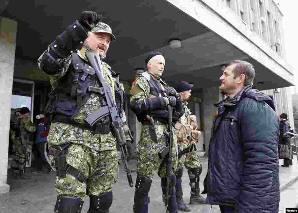 Cư dân nói nói chuyện với dân quân vũ trang thân Nga canh gác bên ngoài văn phòng thị trưởng ở Slaviansk, Ukraine, ngày 14/4/2014.