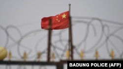 资料照：中国新疆喀什南部一处住宅区墙上的铁丝网与中国国旗。（2019年6月4日）