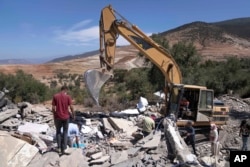 A tractor removes rubble as people search for their belongings in their home which was damaged by the earthquake, in the village of Tafeghaghte, near Marrakech, Morocco, Monday, Sept. 11, 2023. (AP Photo/Mosa'ab Elshamy)