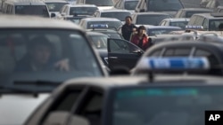 Motorists come out from their vehicle to check as the traffic stand still at a city road in Beijing, China, Tuesday, Nov. 22, 2011.