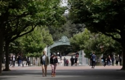 FILE - People walk in front of Sather Gate on the University of California at Berkeley campus in Berkeley, Calif., Thursday, July 18, 2019.