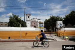 A man rides a bicycle past a church dome which collapsed in an earthquake is seen in Axochiapan, near Mexico City, Mexico September 29, 2017. REUTERS/Henry Romero