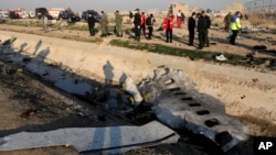 Debris is seen from an Ukrainian plane which crashed as authorities work at the scene in Shahedshahr, southwest of the capital Tehran, Iran, Wednesday, Jan. 8, 2020. (AP Photo/Ebrahim Noroozi)