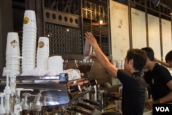 This coffee shop employee is pouring coffee beans into a coffee bean grinder, 2015. (Nov Povleakhena/VOA Khmer)