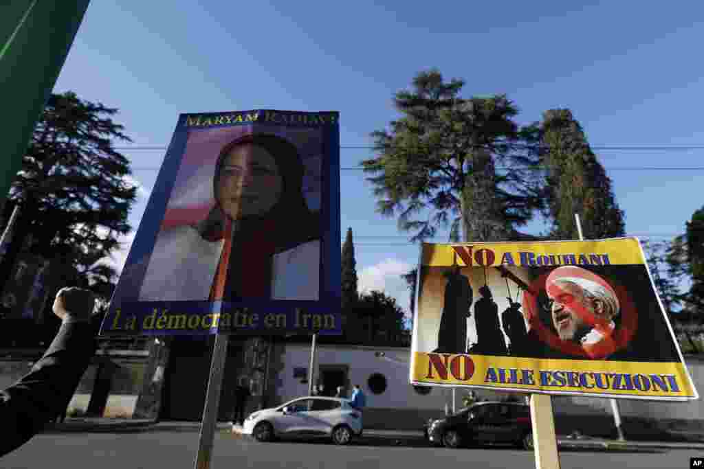 Demonstrators in Rome hold signs showing Maryam Rajavi, head of the Iranian opposition group National Council of Resistance, with writing on placard in French reading, "Democracy in Iran", left, and another one with a picture of Iran President Hassa