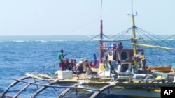 FILE - In this photo provided by Renato Etac, Chinese Coast Guard members, wearing black caps and orange life vests, approach Filipino fishermen as they confront them off Scarborough Shoal at South China Sea in northwestern Philippines, Sept. 23, 2015.