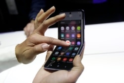 A Samsung worker gives a demonstration of the Galaxy Z Flip Phone at the Unpacked 2020 event in San Francisco, Tuesday, Feb. 11, 2020. (AP Photo/Jeff Chiu)