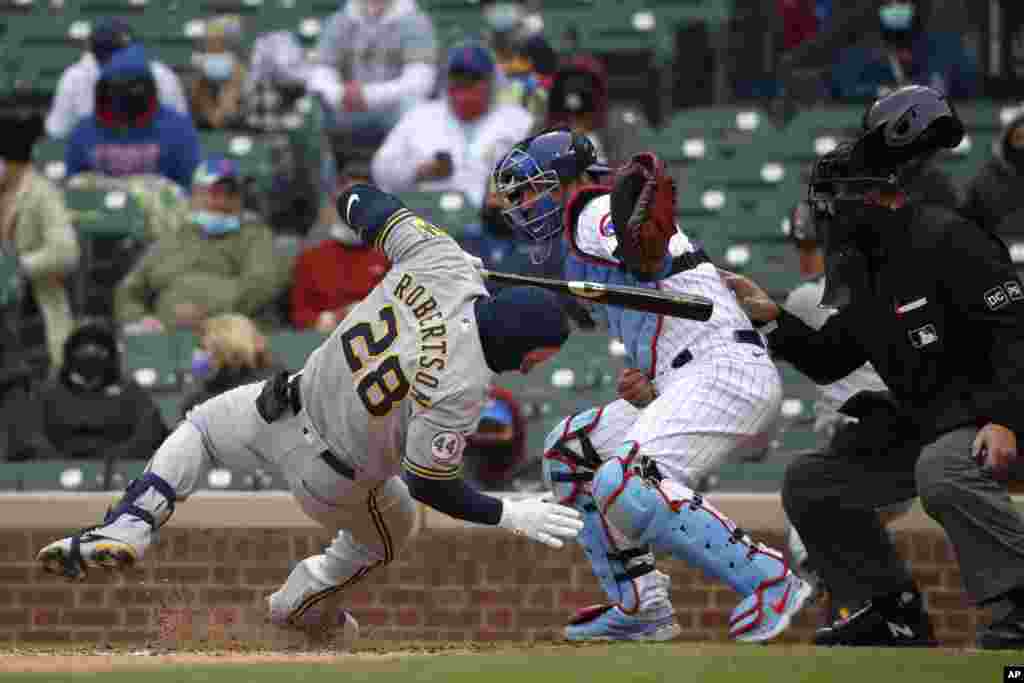 Milwaukee Brewers' Daniel Robertson (28) is hit on the head by a pitch as Chicago Cubs catcher Willson Contreras reaches for the ball during the ninth inning of a baseball game in Chicago, Illinois, April 25, 2021.