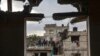 Fotografía tomada a través de la ventana de un edificio dañado por el bombardeo israelí muestra una familia de pie en un tejado, en Rafah, en el sur de la Franja de Gaza, el 27 de enero de 2024, mientras continúan los combates entre Israel y el grupo militante Hamás.