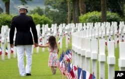 Feelings between soldiers can become quite close. Here, a U.S. Marine Corps soldier holds hands with a small girl as they walk among headstones of World War I dead at the Aisne-Marne American Cemetery in Belleau, France, May 2018.