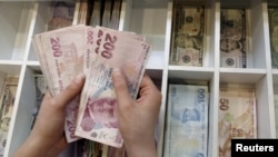 A money changer counts Turkish lira bills at an currency exchange office in central Istanbul, Turkey, Aug. 21, 2015. 