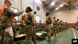In this image provided by the U.S. Army, recent Army basic combat training graduates have their temperatures taken as they arrive at Fort Lee, Va, on March 31, 2020, after being transported using sterilized buses from Fort Jackson, S.C.