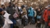 ARCHIVO - Migrantes recogen mantas cerca de un Centro de Asistencia a Migrantes en la Escuela Primaria St. Brigid el martes 5 de diciembre de 2023 en Nueva York.