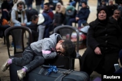 A girl sleeps on a suitcase as she waits with her family for a travel permit to cross into Egypt through the Rafah border crossing after it was opened by Egyptian authorities for humanitarian cases, in the southern Gaza Strip February 8, 2018.