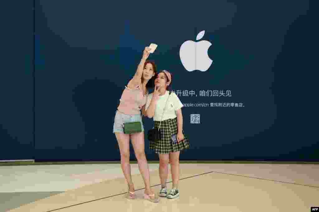 2018年8月16日，女子在北京一家购物中心里正在施工翻新的苹果商店前摆姿势拍照。