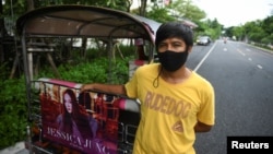 Tuk-tuk driver Samran Thammasa stands next to his vehicle decorated with a banner of K-pop star Jessica Jung, as he waits for customers, in Bangkok, Thailand May 12, 2021. (REUTERS/Chalinee Thirasupa)