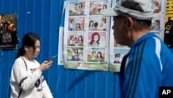 People walk past a poster warning against foreign spies in an alley in Beijing, China, April 20, 2016. China is marking National Security Education Day with the poster warning female government workers about dating foreigners, who could turn out to have secret agendas. (AP Photo/Ng Han Guan) 