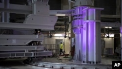 A worker walks through large assembly tools in the assembly hall of the ITER ( the International Thermonuclear Experimental Reactor). The project aims to replicate the energy of the sun to create nuclear fusion reactions as a way to produce power. (AP Photo/Daniel Cole)