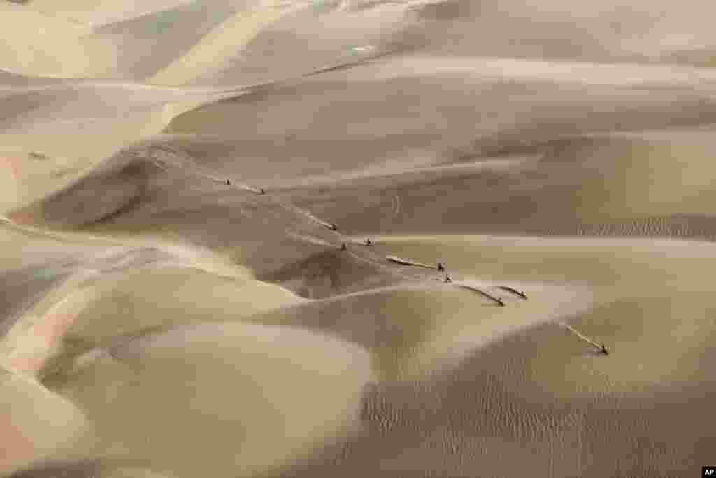 Racers ride their motorcycles across the sand during the Dakar Rally in Pisco, Peru, on January 16, 2019. (AP Photo/Ricardo Mazalan)