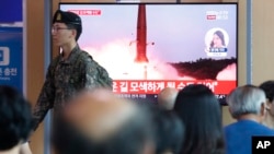A South Korean army soldier passes by a TV screen showing a file image of North Korea's missile launch during a news program at the Seoul Railway Station in Seoul, South Korea, Tuesday, Aug. 6, 2019.