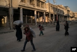 FILE - Children and women carry metal scraps they collected from the rubble in the Old City of Mosul, Iraq, Nov. 16, 2017.