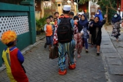 Hendrawan and his son are greeted by children as they arrive to teach. (REUTERS/Willy Kurniawan)