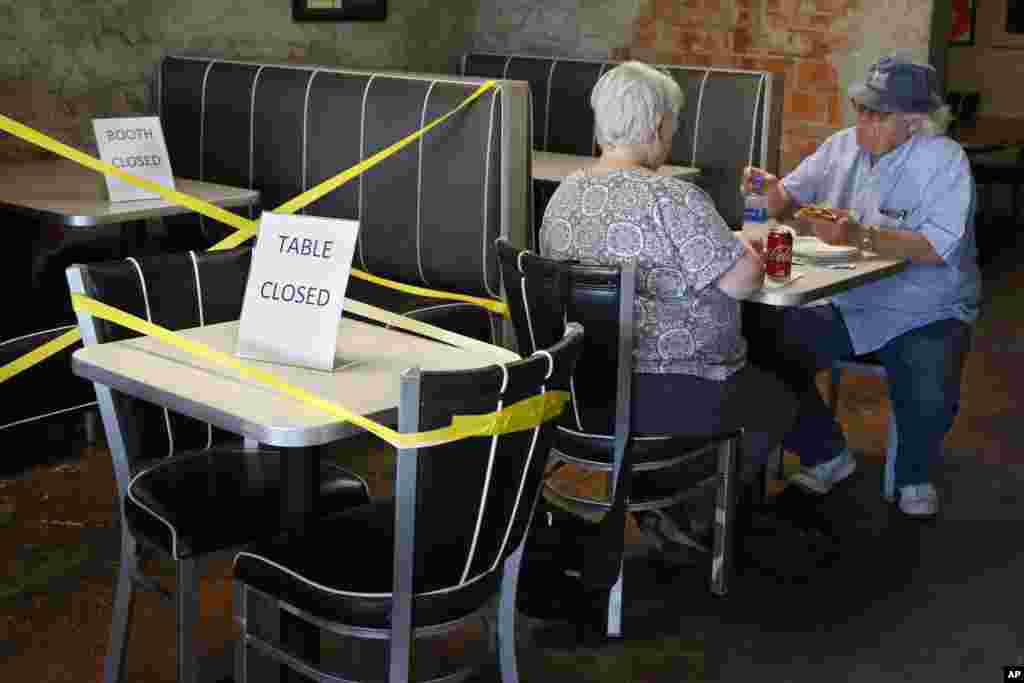 George Kolokotronex, right, and his wife, Nancy Kolokotronex, left, eat lunch at Falcone's Pizzeria Friday, May 1, 2020, in Oklahoma City, as restaurants are allowed to open for in person dining. Tables are taped off to promote social distancing. (AP Phot