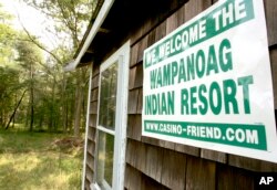FILE — A poster declaring support for bringing a casino to Middleborough, Mass., appears on the side of a small house on property adjacent to land belonging to the Mashpee Wampanoag tribe.