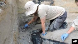 In this photo provided by researchers, an excavation team uncovers a wooden structure found on a riverbed near a waterfall in Zambia in 2019. (Larry Barham/University of Liverpool via AP)