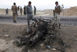 FILE - Afghan security forces gather at the site of Monday's suicide attack near the Bagram Air Base, north of Kabul, Afghanistan, April 9, 2019.