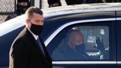 U.S. President Joe Biden waves through the window of a car during the Inauguration Day parade
