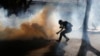 Un manifestante recupera un fraco de gas lacrimógeno lanzado por las fuerzas de seguridad durante una protesta que se dirigía hacia la sede del Consejo Electoral Nacional en Caracas.