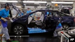 In this Oct. 30, 2017, photo, workers of a Toyota Motor Corp. assemble a Mirai fuel cell vehicle at the automaker's Motomachi plant in Toyota, western Japan. (AP Photo/Yuri Kageyama)