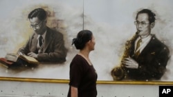 A woman passes by drawing portraits of the late Thai King Bhumibol Adulyadej in Bangkok, Thailand, Tuesday, Oct. 18, 2016. Thailand's late King Bhumibol Adulyadej was known for playing with some of the world's jazz legends. (AP Photo/Sakchai Lalit)