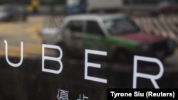 A taxi is reflected in a window at the office of taxi-hailing service Uber Inc in Hong Kong, China August 12, 2015.