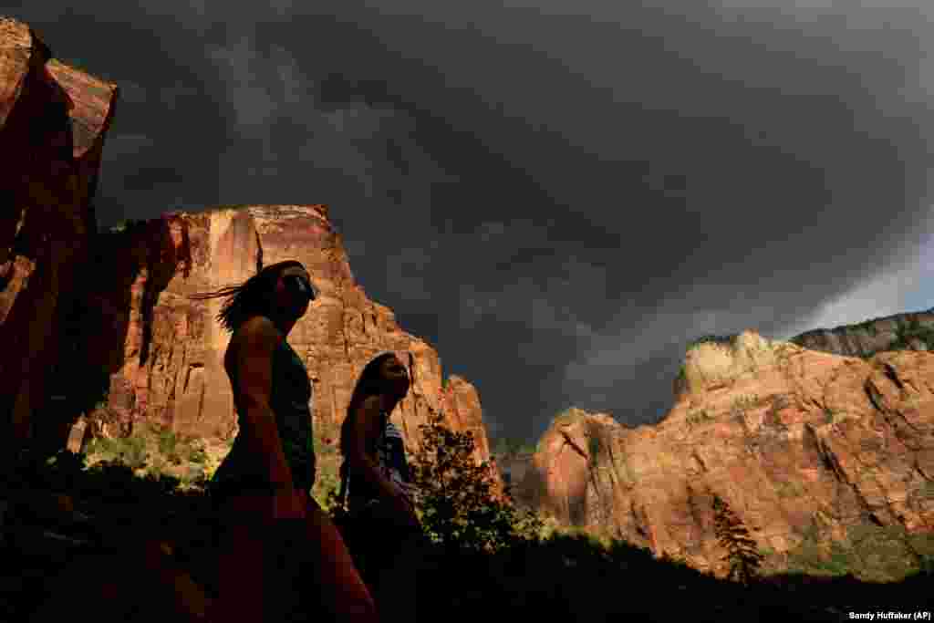 Hikers look up at a fast moving storm as it makes its way through Zion National Park outside of Springdale, Utah. Many of the country's most prominent national parks, including Grand Canyon, Yellowstone and Zion, set new visitation records in 2015.