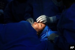 In this Tuesday, Nov. 6, 2018 photo, plastic surgeon Dr. Abbas al-Sahan performs reconstructive surgery on Saja Ahmed Saleem, in Baghdad, Iraq. (AP Photo/Hadi Mizban)