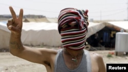 Penaberekî Kurd yê Sûrî li kampeke penaberan ya li bajarê Zaxoyê nîşana serkeftinê dike. Hezîran 23, 2012. 