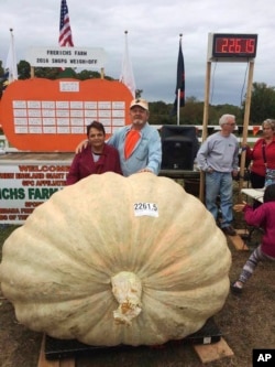 Richard and Catherine Wallace stand with a 1,026 kg. pumpkin that Richard grew to set the North American giant pumpkin record at the Frerichs Farm Pumpkin Weigh Off in Warren, R.I.