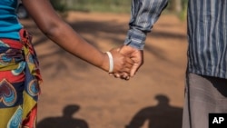 A 15-year-old pregnant girl holds hands with her 20-year-old husband-to-be in Mozambique, Nov. 18, 2015. (AP)