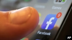 FILE - An iPhone displays the Facebook app in New Orleans, August 11, 2019. (AP Photo/Jenny Kane, File)