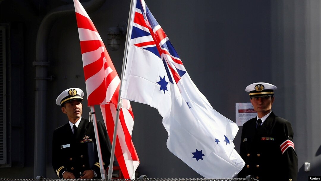 日澳海軍在澳大利亞悉尼一軍事基地舉行聯合軍演前兩國軍人在日澳兩軍旗幟旁合影。（2016年4月19日）