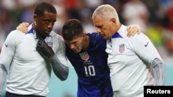 Christian Pulisic of the U.S. receives medical attention after colliding with Iran's Alireza Beiranvand after scoring the first goal on November 29, 2022. (REUTERS/Kai Pfaffenbach)